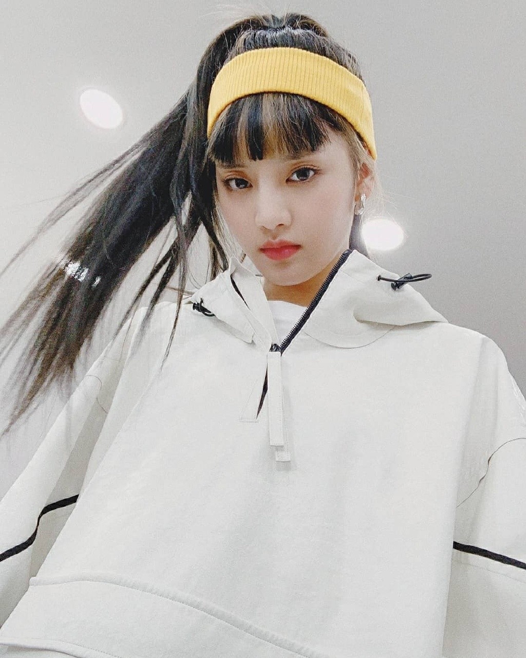 她是组合梦幻主唱，穿白底黑线休闲套装，发带增加运动感